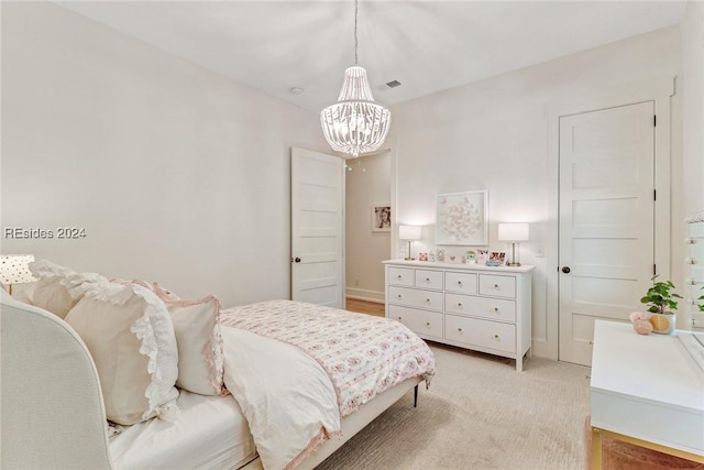 bedroom with light colored carpet and an inviting chandelier