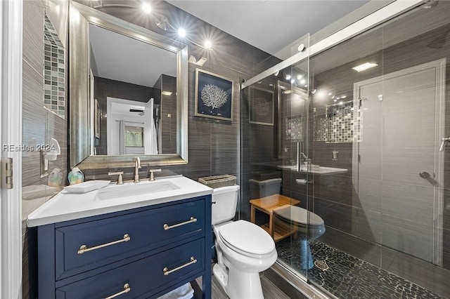 bathroom with tile walls, vanity, toilet, and walk in shower