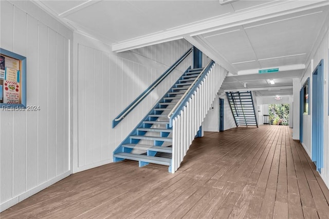 stairway featuring coffered ceiling and hardwood / wood-style floors