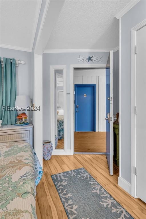 bedroom featuring hardwood / wood-style flooring, ornamental molding, and a textured ceiling