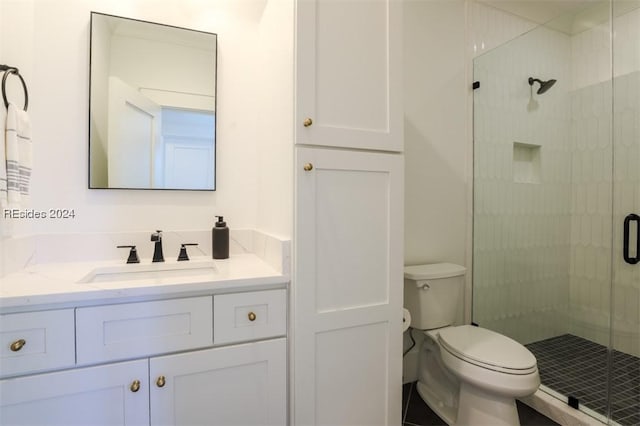 bathroom featuring vanity, a shower with shower door, and toilet