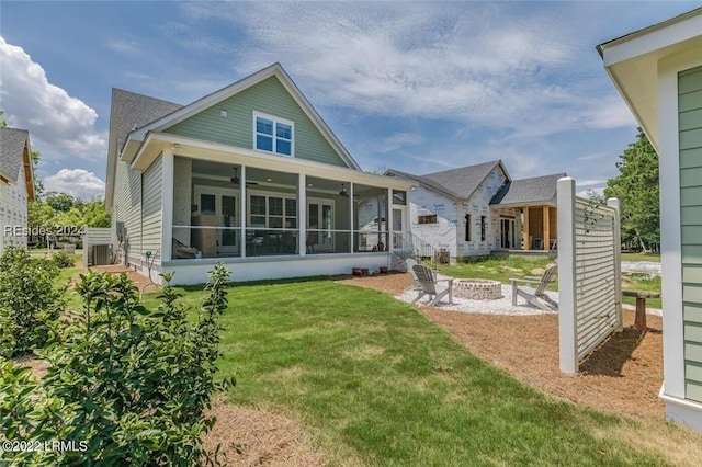 back of house featuring a sunroom, a yard, ceiling fan, and an outdoor fire pit