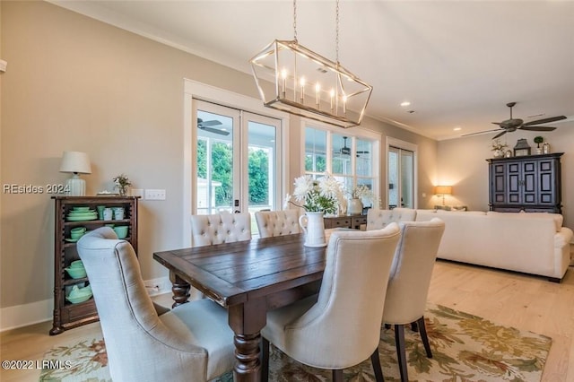 dining space featuring ceiling fan with notable chandelier, light hardwood / wood-style flooring, ornamental molding, and french doors