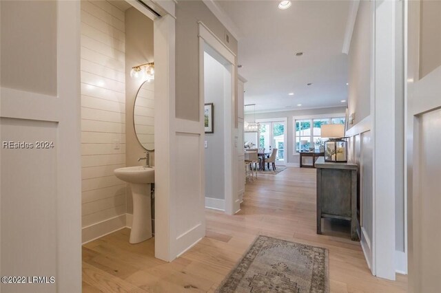 hall with sink, ornamental molding, and light wood-type flooring