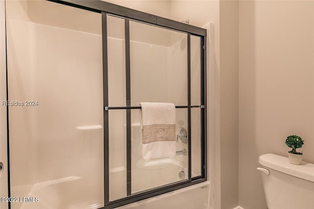 bathroom featuring bath / shower combo with glass door and toilet