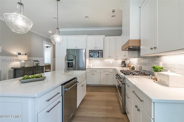 kitchen featuring light hardwood / wood-style flooring, white cabinetry, a kitchen island with sink, high quality appliances, and decorative light fixtures