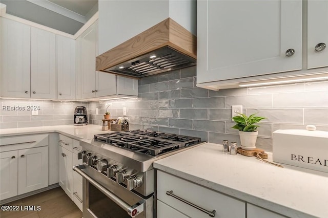 kitchen with backsplash, stainless steel range, custom exhaust hood, and white cabinets