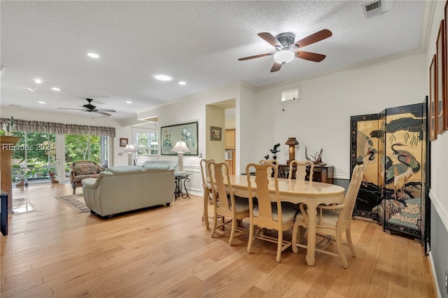 dining room with ornamental molding, light hardwood / wood-style floors, and a textured ceiling