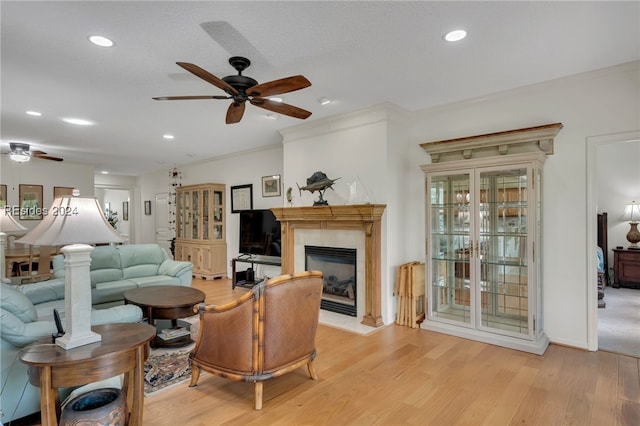 living room with ceiling fan, ornamental molding, and light hardwood / wood-style floors