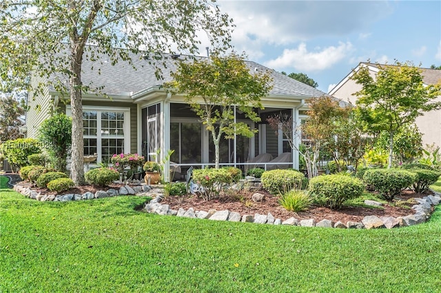 back of property with a sunroom and a lawn