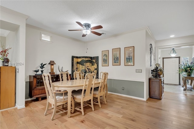 dining area featuring ceiling fan, crown molding, a textured ceiling, and light wood-type flooring