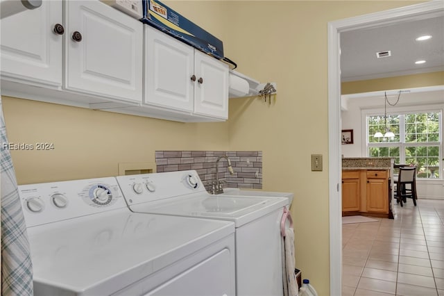 laundry room with light tile patterned floors, sink, washing machine and dryer, cabinets, and ornamental molding