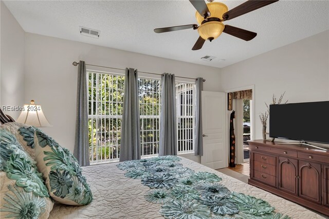 bedroom with ceiling fan, a textured ceiling, and access to outside