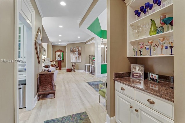 interior space featuring white cabinetry, ornamental molding, and dark stone counters