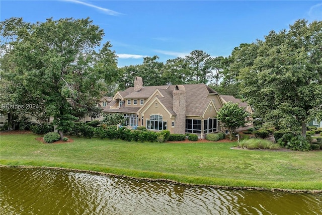 rear view of house featuring a water view and a yard