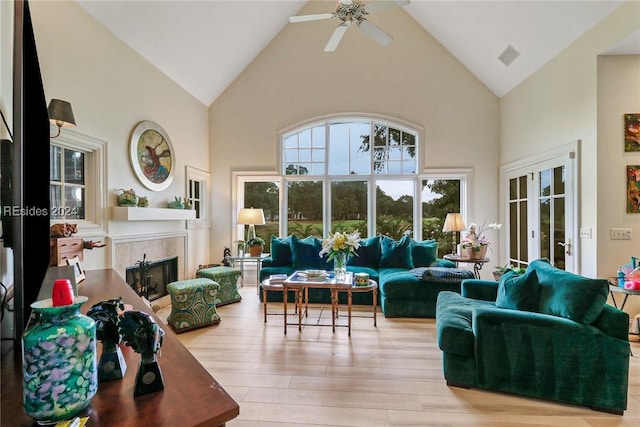 living room with high vaulted ceiling, a fireplace, light hardwood / wood-style floors, and ceiling fan