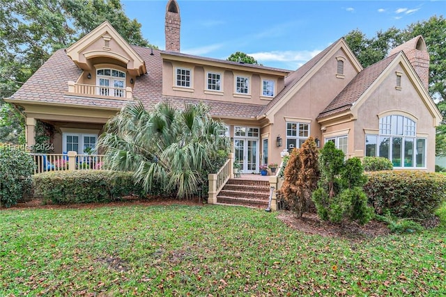 back of property featuring a lawn, french doors, and a balcony