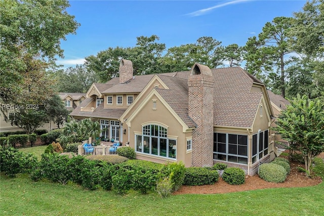 rear view of house featuring a yard and a sunroom