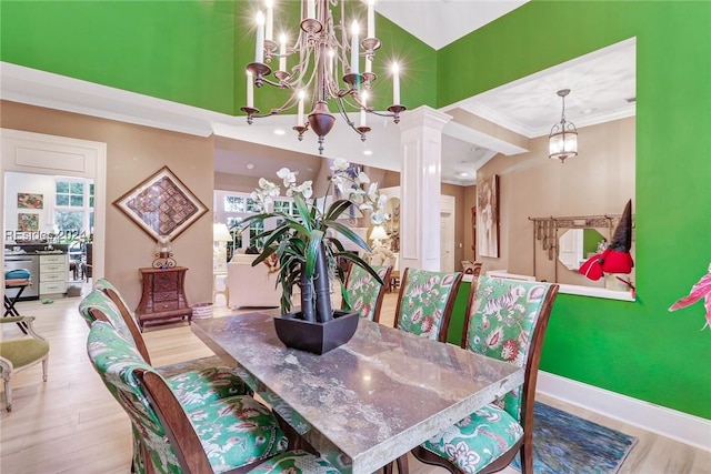 dining room featuring crown molding, a chandelier, light hardwood / wood-style floors, and decorative columns