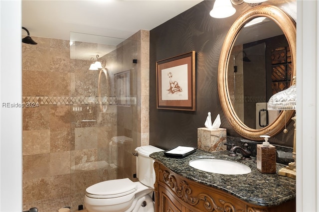 bathroom with vanity, toilet, and a tile shower