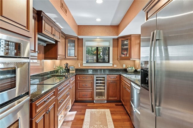 kitchen featuring wine cooler, sink, appliances with stainless steel finishes, dark stone counters, and light hardwood / wood-style floors