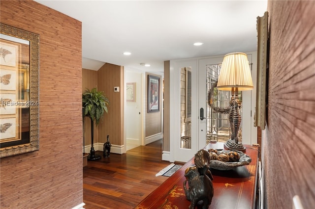 hall featuring brick wall and dark wood-type flooring