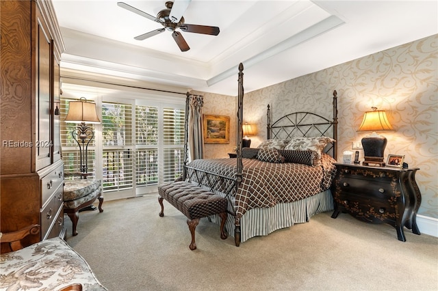 carpeted bedroom with a raised ceiling, crown molding, and ceiling fan