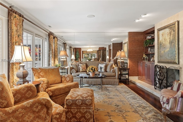 living room with dark wood-type flooring, built in shelves, and a notable chandelier