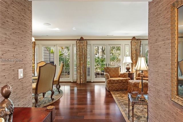 living room with dark hardwood / wood-style flooring, ornamental molding, and a healthy amount of sunlight