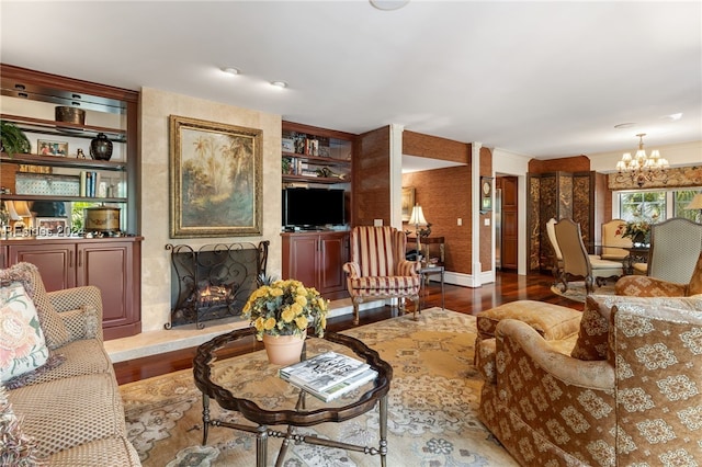 living room featuring a notable chandelier, built in shelves, a large fireplace, and hardwood / wood-style flooring