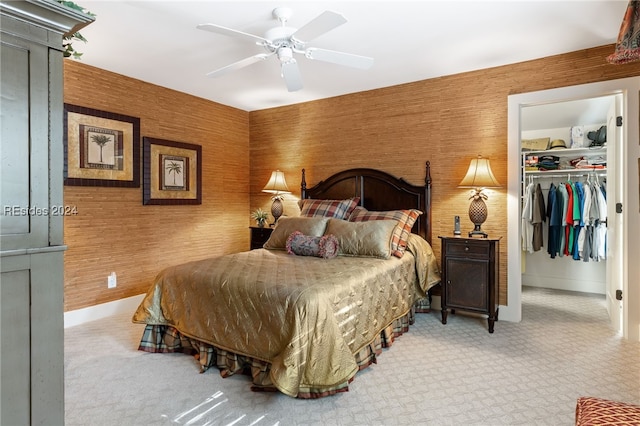 bedroom featuring wooden walls, a closet, ceiling fan, and carpet