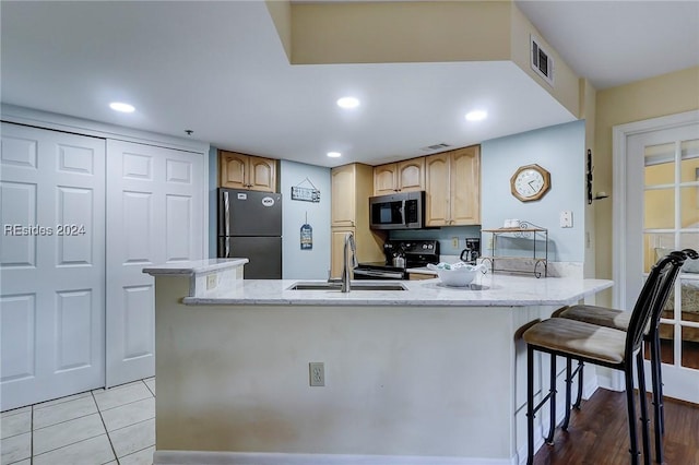 kitchen with sink, light tile patterned floors, black appliances, light brown cabinetry, and kitchen peninsula