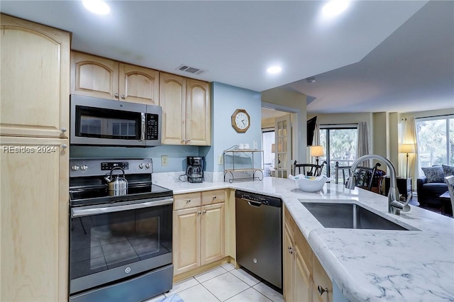 kitchen with sink, light tile patterned flooring, light brown cabinets, and appliances with stainless steel finishes