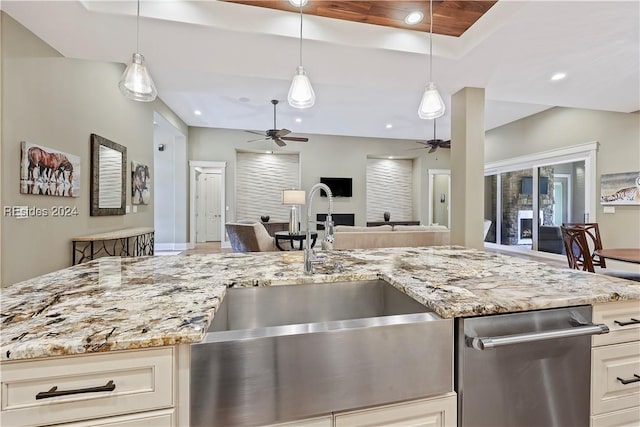 kitchen featuring pendant lighting, sink, light stone countertops, and a raised ceiling