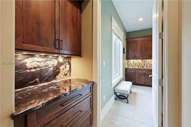 bar with backsplash, a healthy amount of sunlight, sink, and dark stone countertops