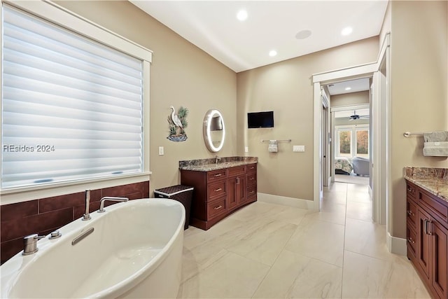 bathroom with a tub to relax in, vanity, and tile patterned floors