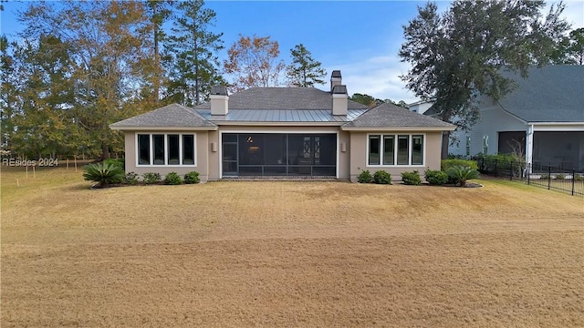 rear view of house with a yard and a sunroom