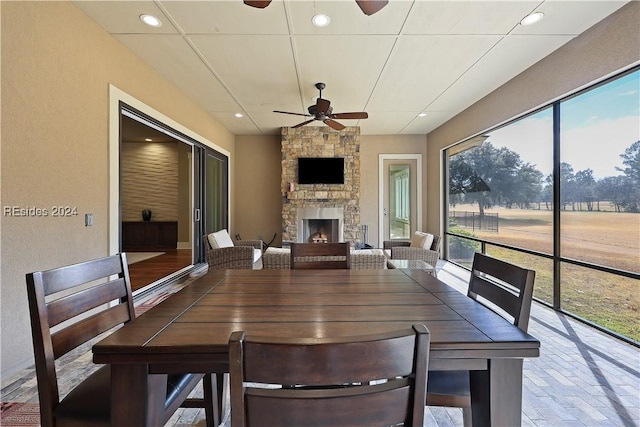 dining space with ceiling fan and a fireplace