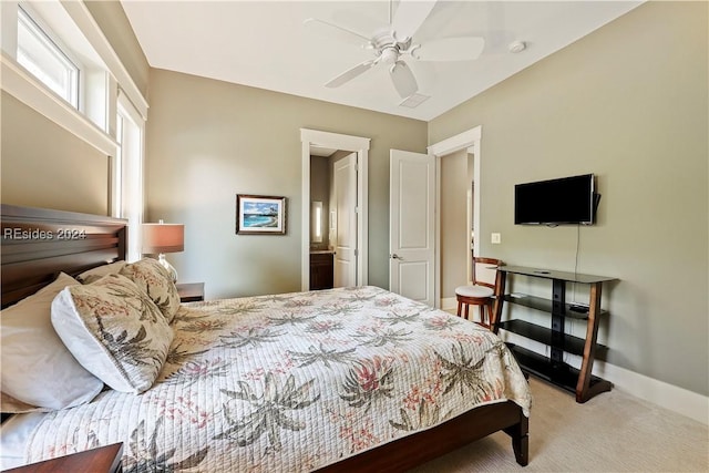 bedroom with light carpet, connected bathroom, and ceiling fan