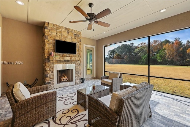 sunroom featuring ceiling fan and an outdoor stone fireplace