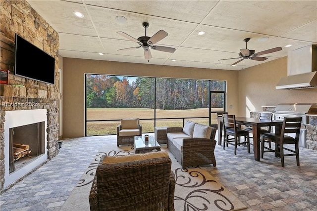 living room featuring a stone fireplace and ceiling fan