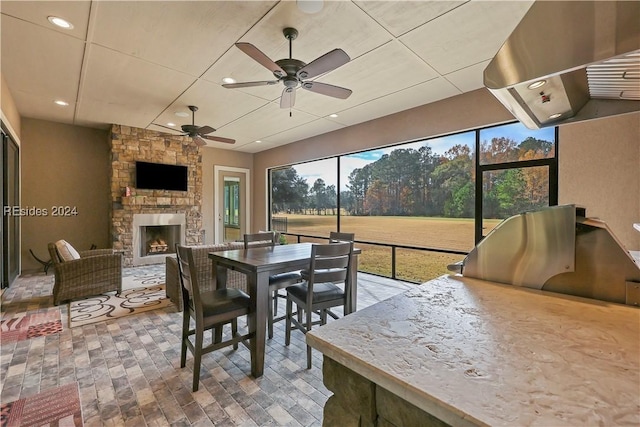 sunroom featuring ceiling fan and a fireplace