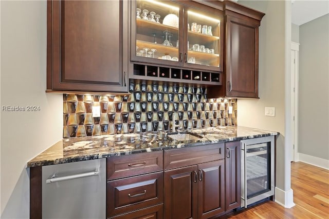 bar featuring tasteful backsplash, light hardwood / wood-style flooring, beverage cooler, and dark stone counters