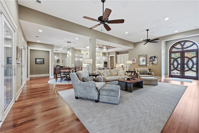 living room featuring french doors, ceiling fan, and light hardwood / wood-style floors