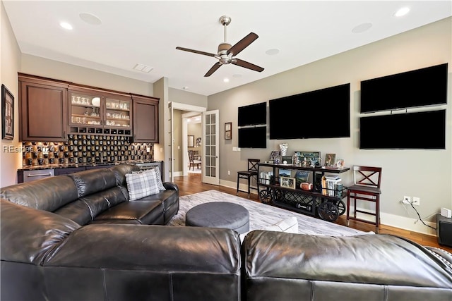 living room with hardwood / wood-style flooring, indoor bar, ceiling fan, and french doors