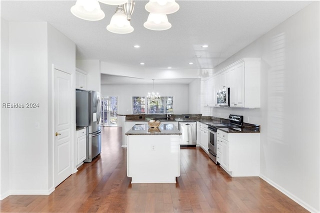 kitchen with a chandelier, a center island, appliances with stainless steel finishes, pendant lighting, and white cabinets