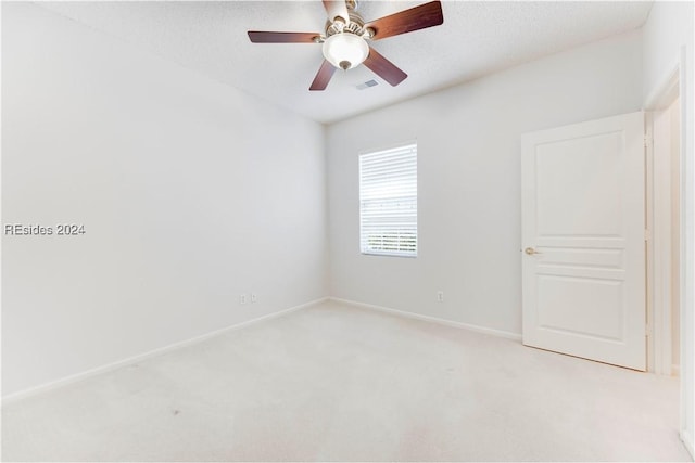 carpeted spare room featuring a textured ceiling and ceiling fan