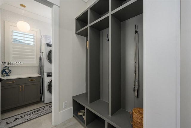 mudroom featuring light tile patterned flooring and stacked washing maching and dryer