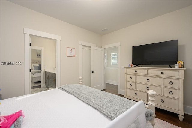 bedroom featuring ensuite bath and dark hardwood / wood-style floors