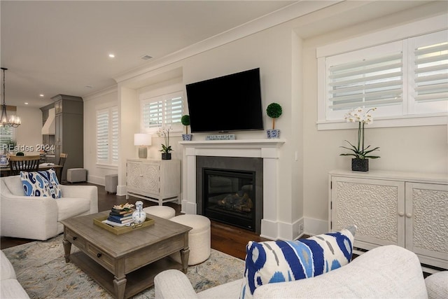 living room featuring hardwood / wood-style flooring, crown molding, and an inviting chandelier